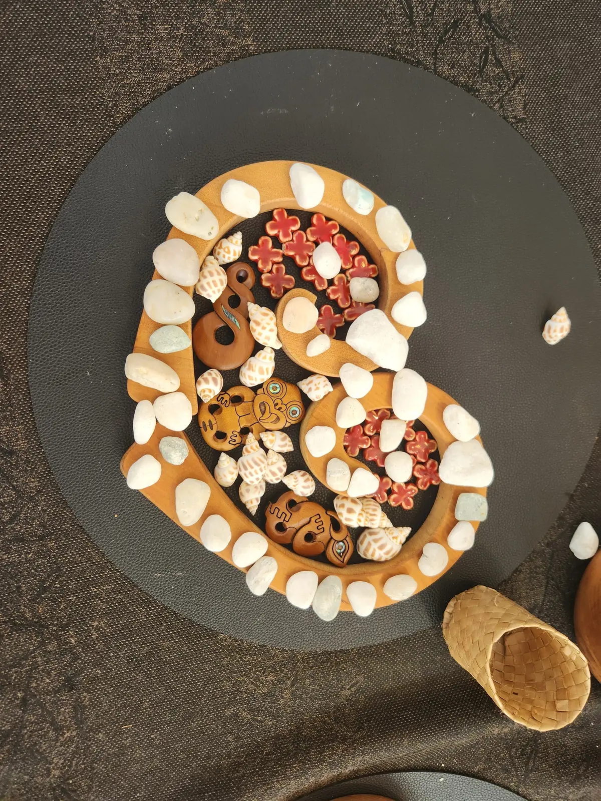 A wooden koru filled with shells and red flowers.