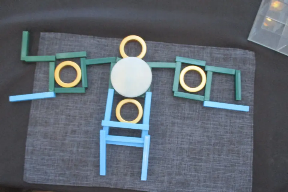 A pattern of rods and rings on a grey mat.