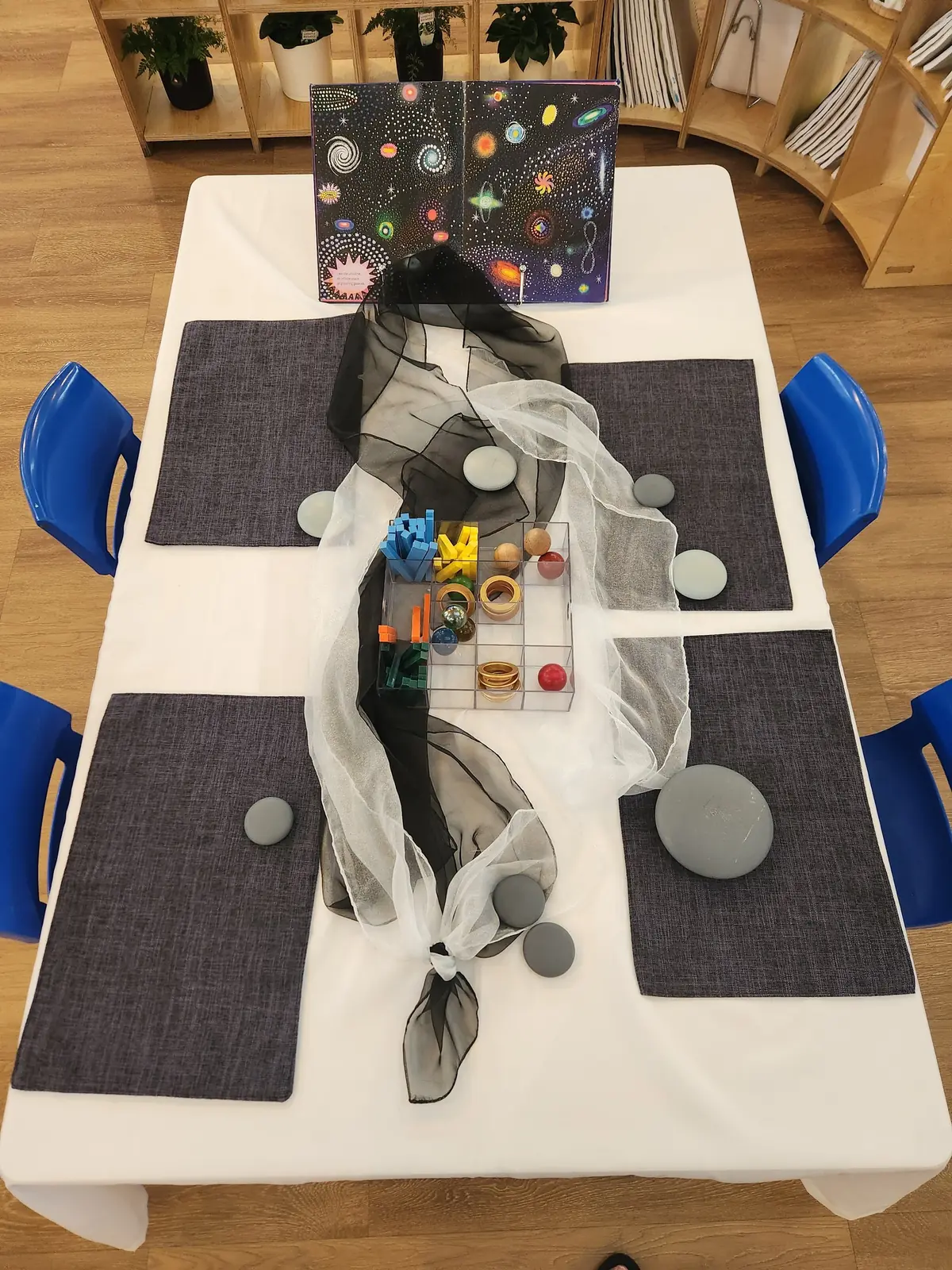 A table set for exploring, with mats, stones, fabric and a space poster.